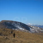 A group of hikers walking to Puig Estela peak direction photograph, with some snowed peaks on the background inside Serra Cavallera, Girona.