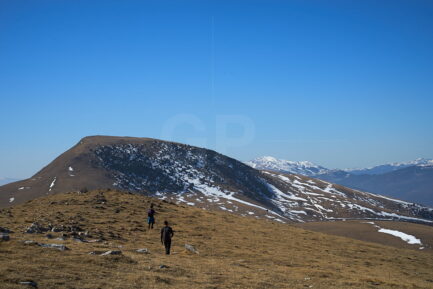 A group of hikers walking to Puig Estela peak direction photograph, with some snowed peaks on the background inside Serra Cavallera, Girona.