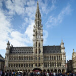 Horizontal photograph of Brussels Town Hall with people in the Grand Place