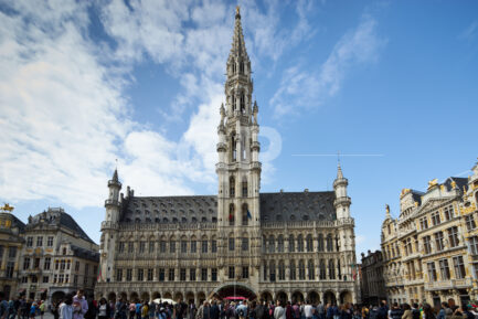 Horizontal photograph of Brussels Town Hall with people in the Grand Place﻿